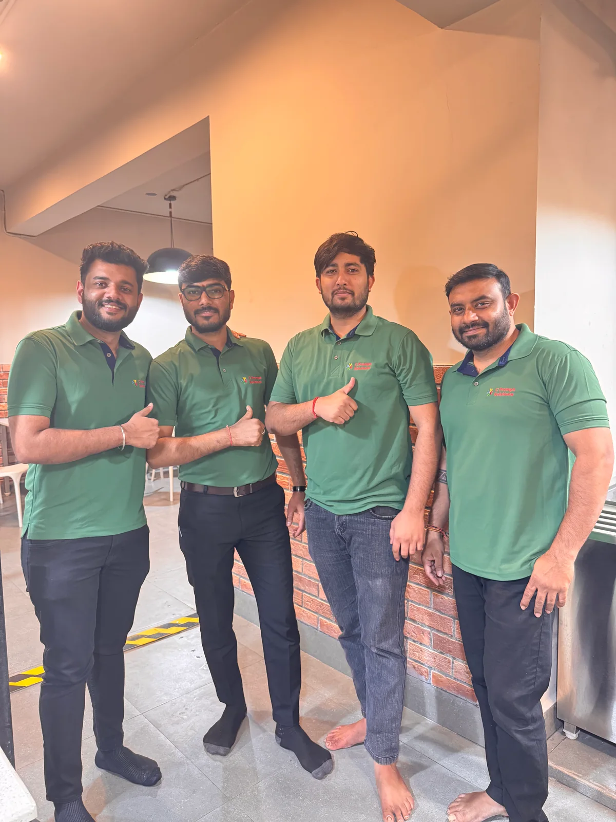 C Prompt colleagues in green polo shirts standing together indoors.