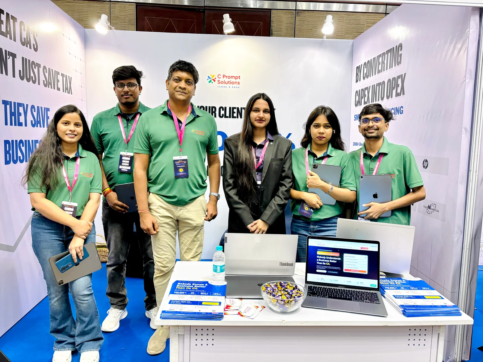 C Prompt exhibition team beside a laptop display.